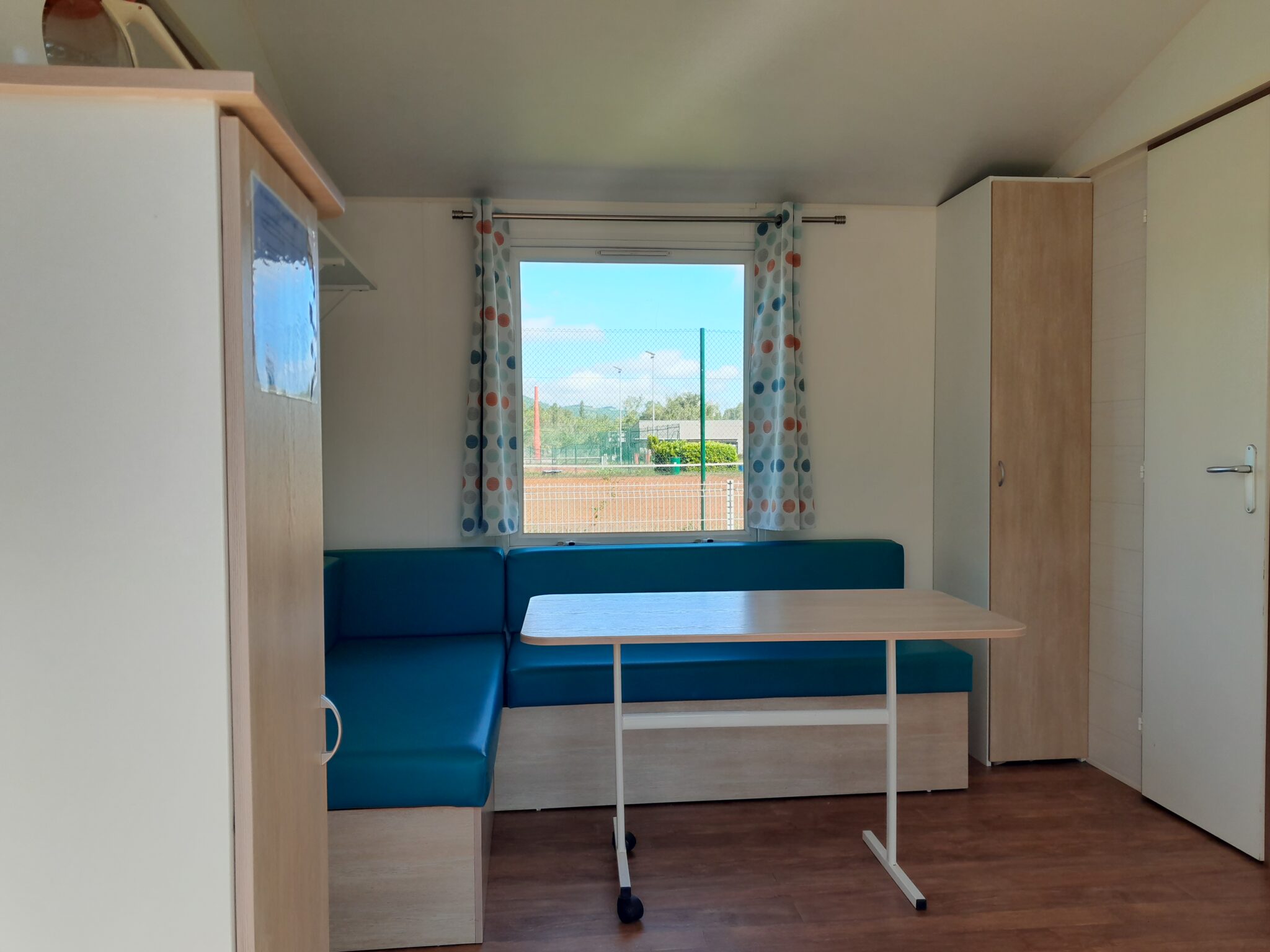 Vue salon dans le mobilhome type bungalow avec table et canapé pour location de mobil-home à Saint-Vallier